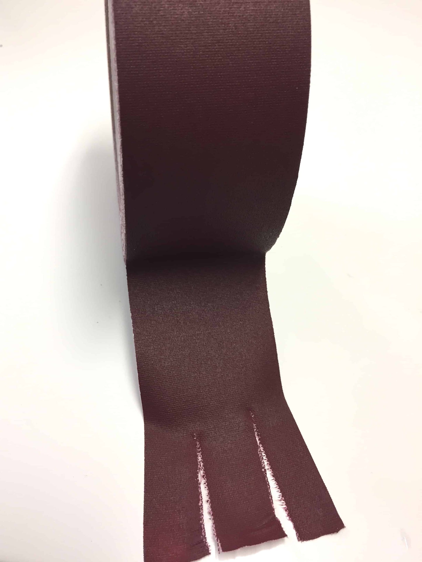 Burgundy gaffer tape pieces torn cleanly from roll demonstrating flexible cloth tape design