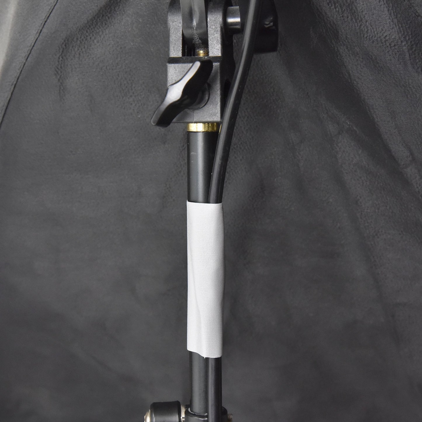 Grey gaffer tape attaching electrical cable to light stand for clean cable routing on film or photography set